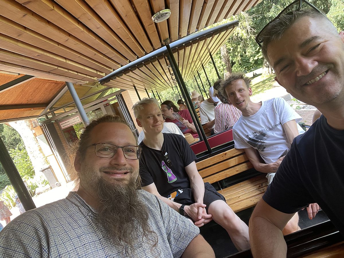 Men sitting in a small open train carriage.