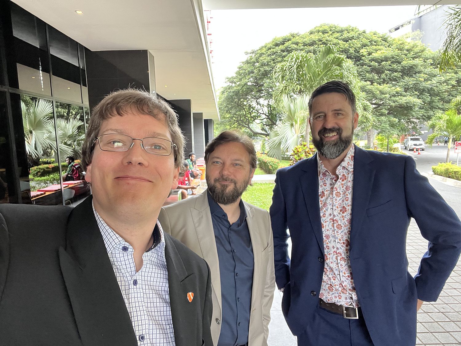 Selfie with three men in suit jackets, smiling and looking at camera.